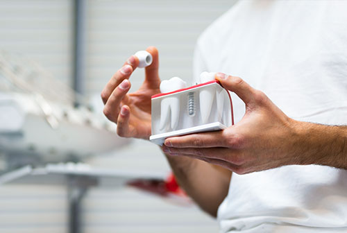The image shows a person holding an electric toothbrush with its head facing downwards, set against a backdrop of industrial machinery and equipment.